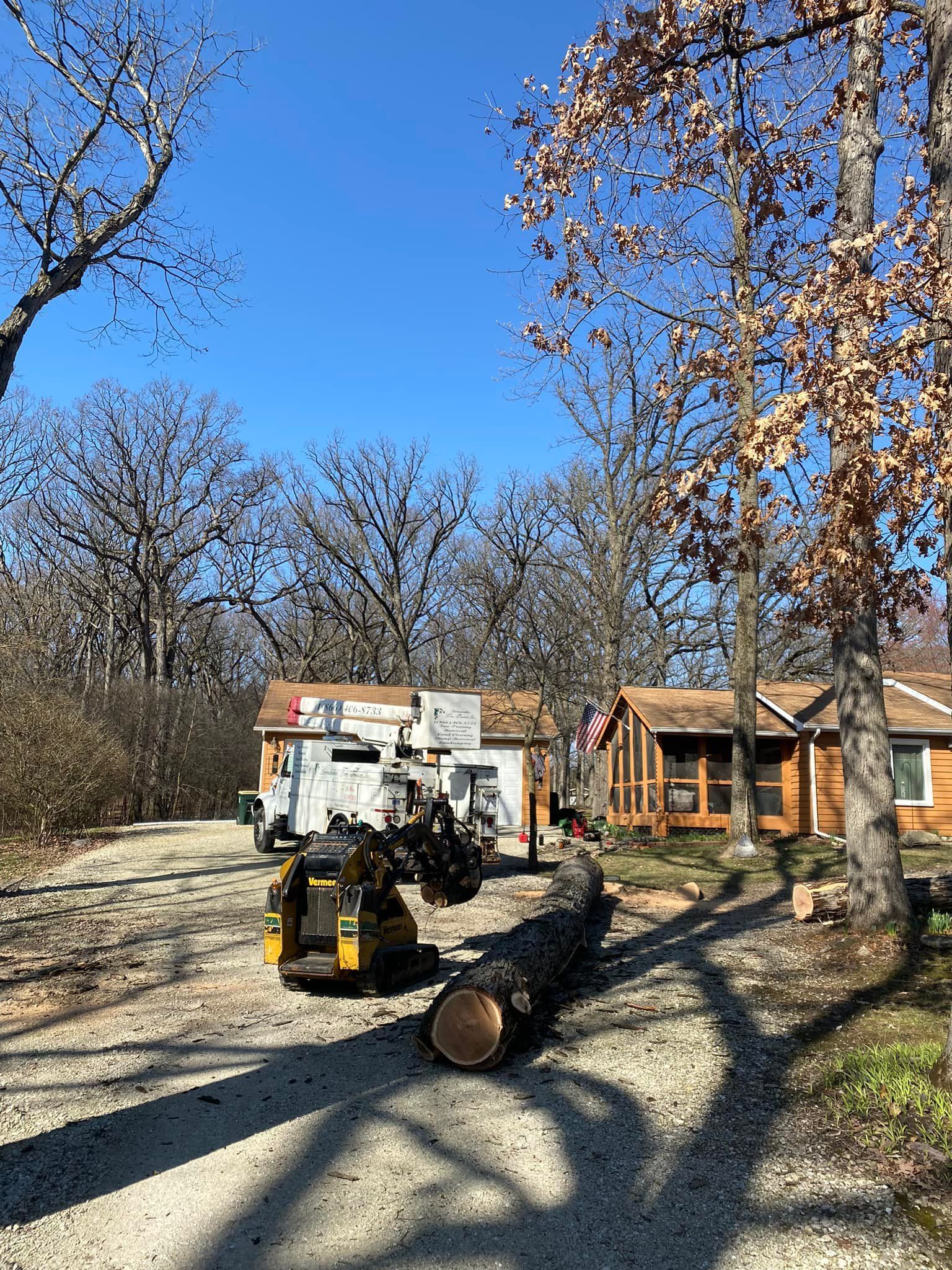 A large log is sitting on the side of the road in front of a house.