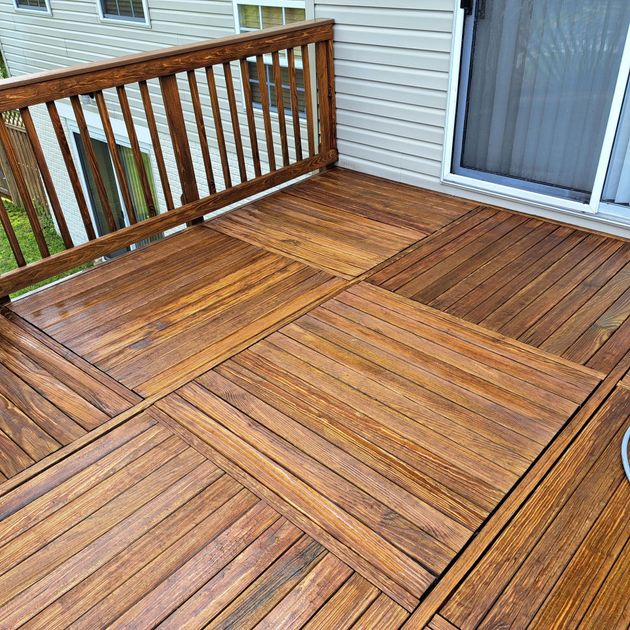 Wooden deck with diagonal plank pattern and railing beside a house sliding glass door.