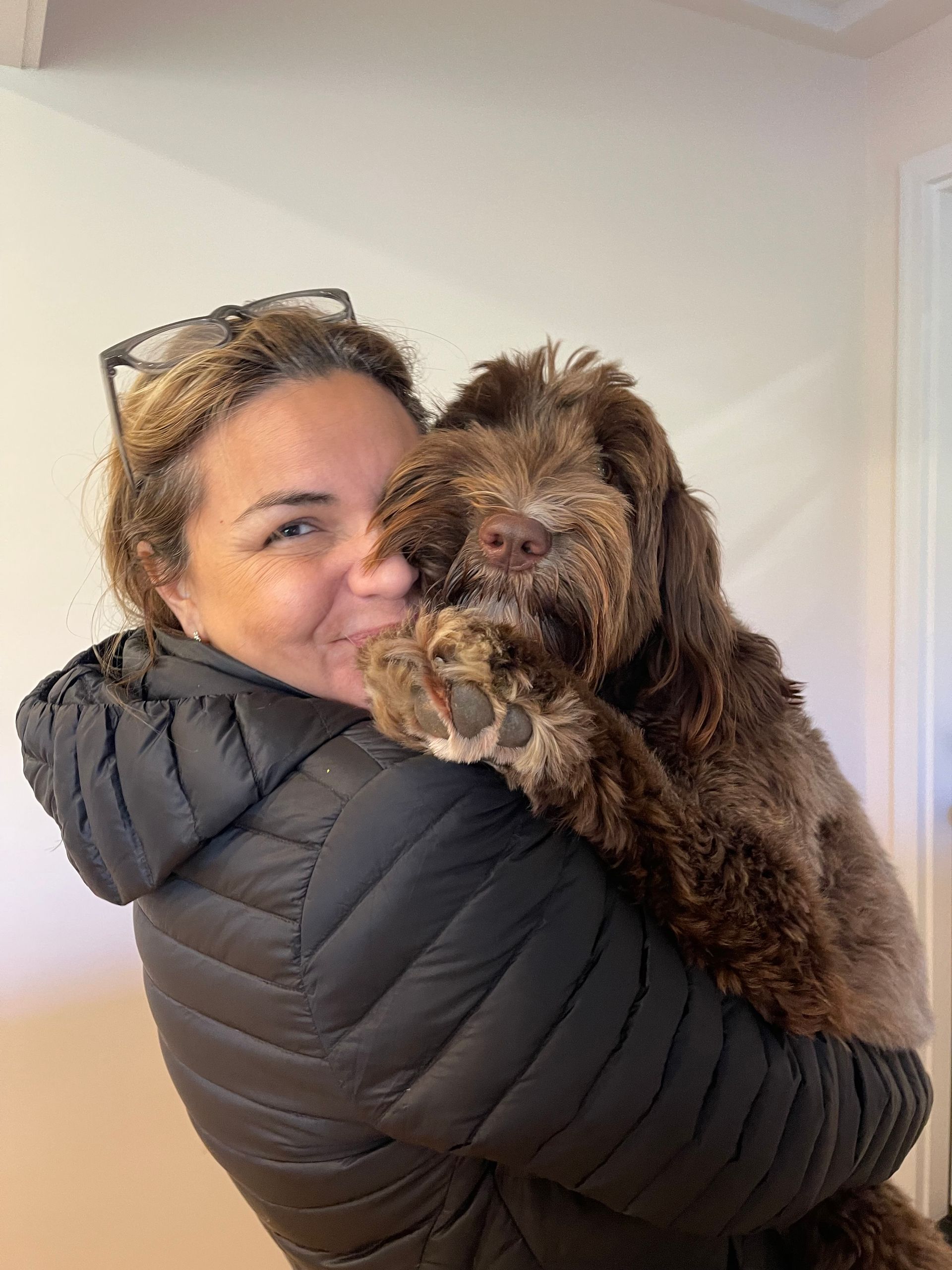 A woman is holding a brown dog in her arms