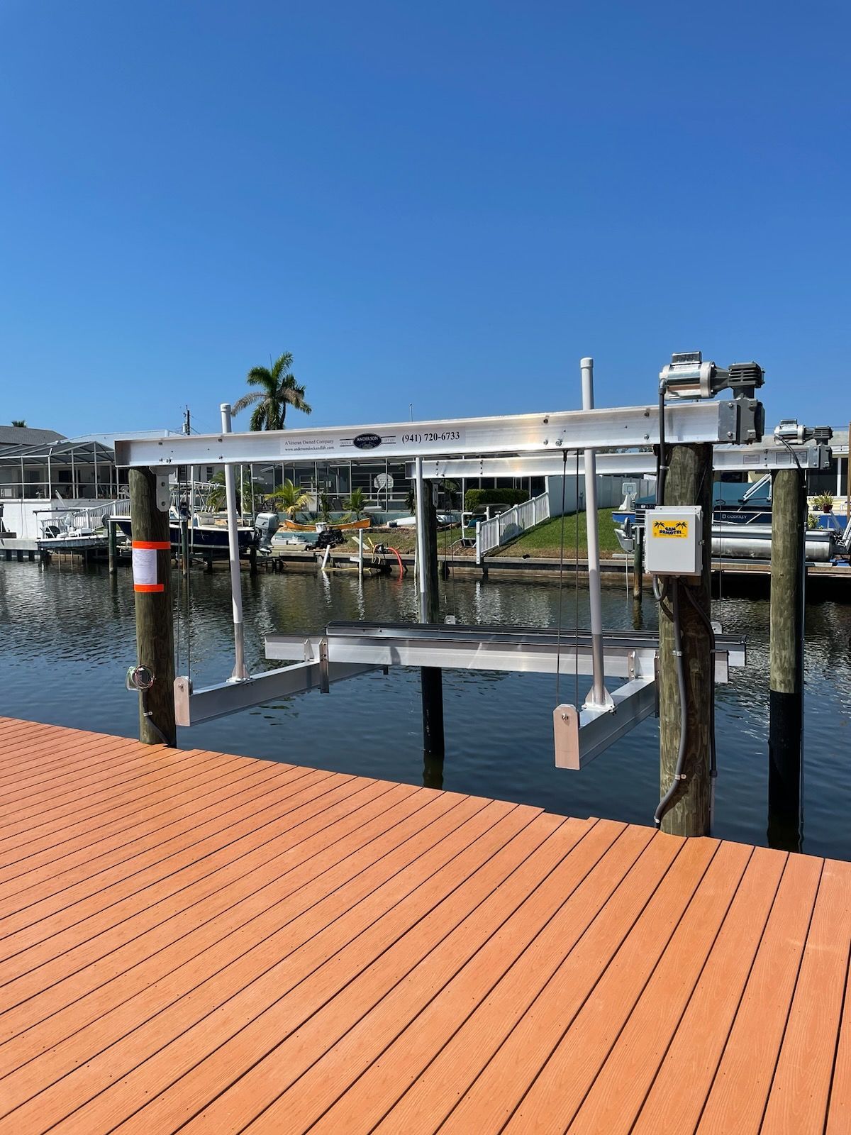 Boat lift at a dock in a canal with a blue sky.