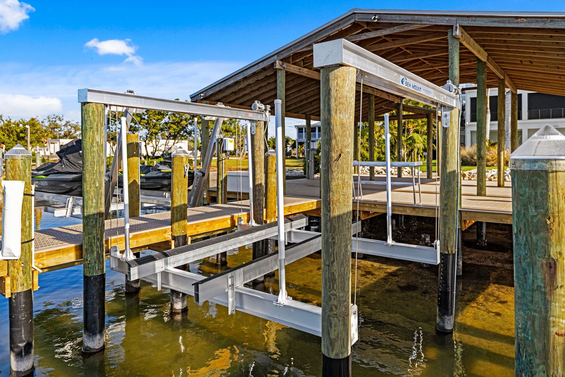 Boat lift on a dock with wooden posts, under a canopy. Water surrounds it.