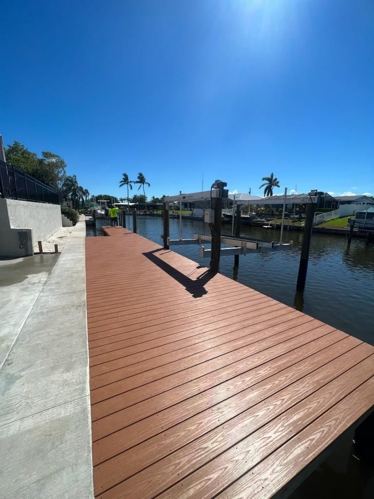 Brown composite dock extending into canal under a bright blue sky.
