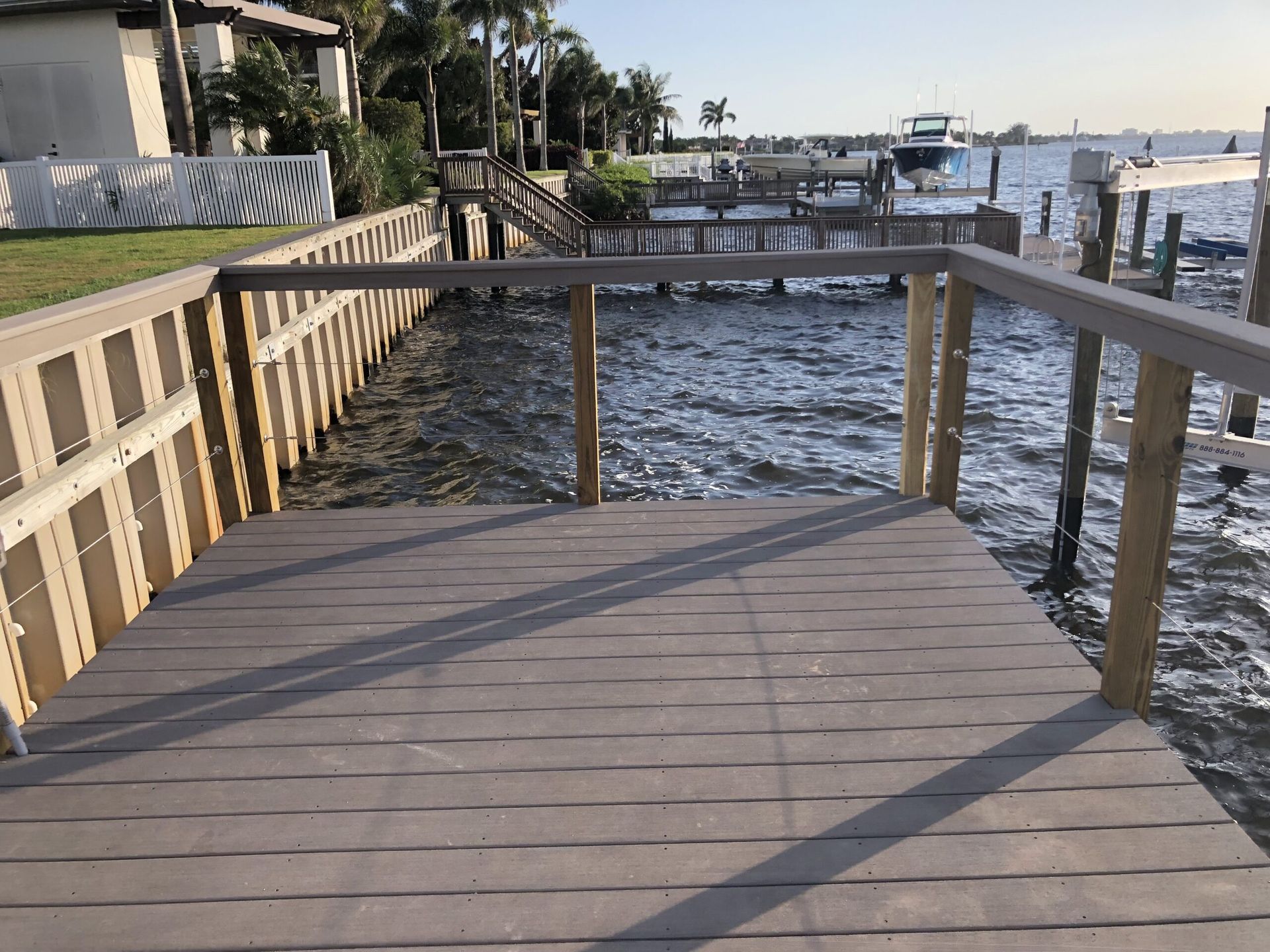 Wooden dock extending to a body of water with other docks and a boat visible in the distance.