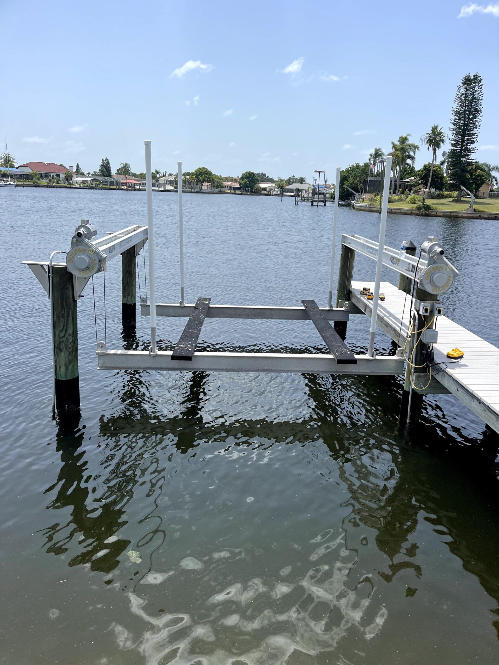 Boat lift on a wooden dock in a waterway, sunny day.