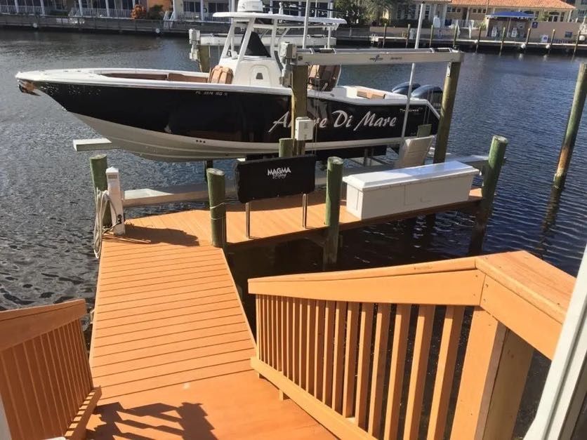 Boat on a lift over water, accessible by wooden stairs. The boat is black and white.