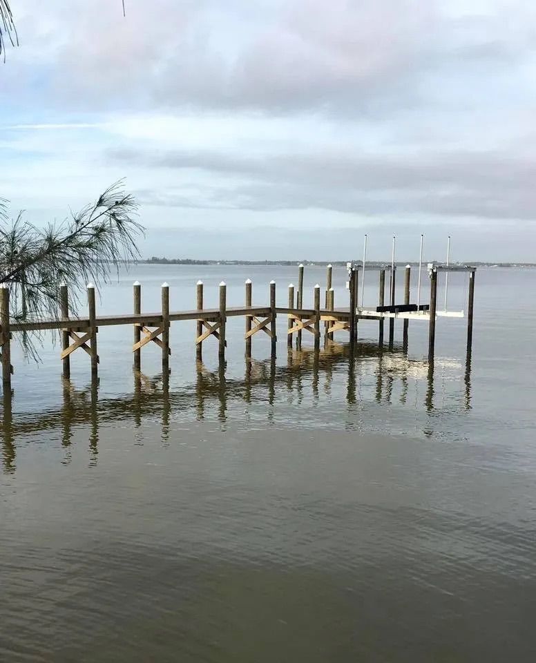 Wooden dock extending into calm water under a cloudy sky.