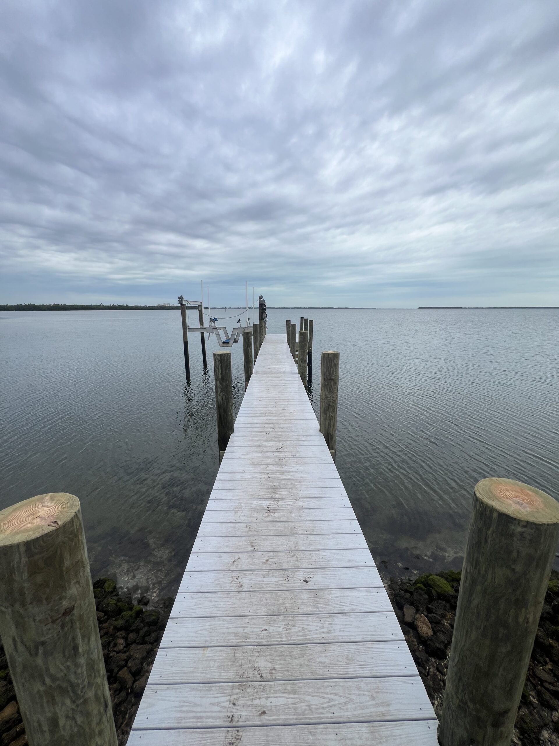 Wooden pier stretches over calm water under a cloudy sky.