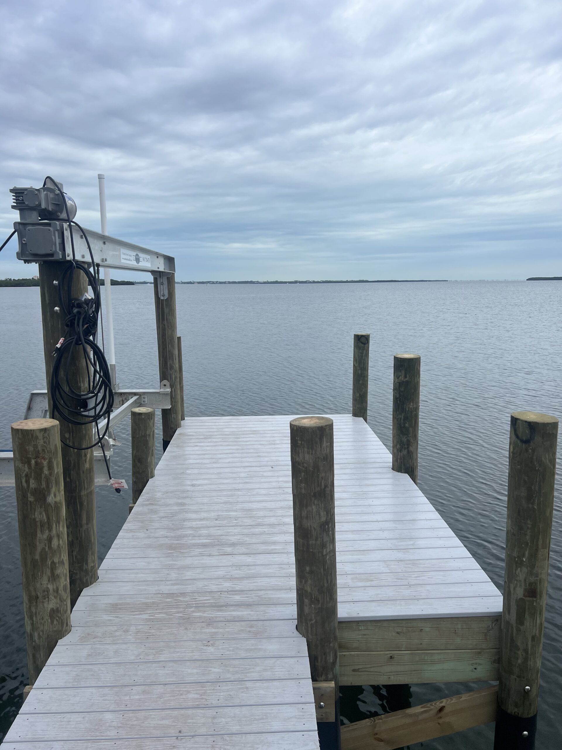 Wooden dock extending into calm water under a cloudy sky.