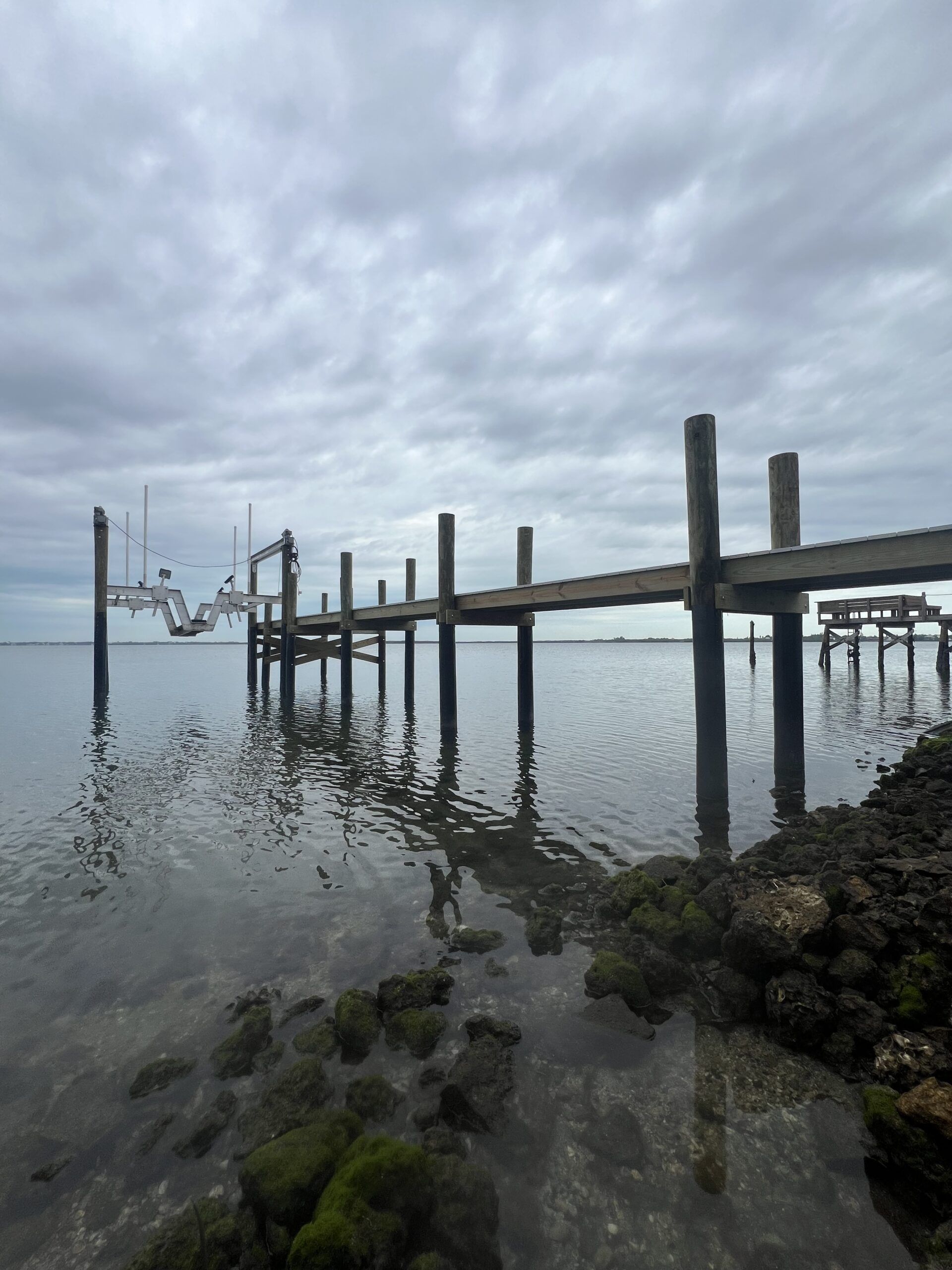 Wooden pier extends into calm water under a cloudy sky.