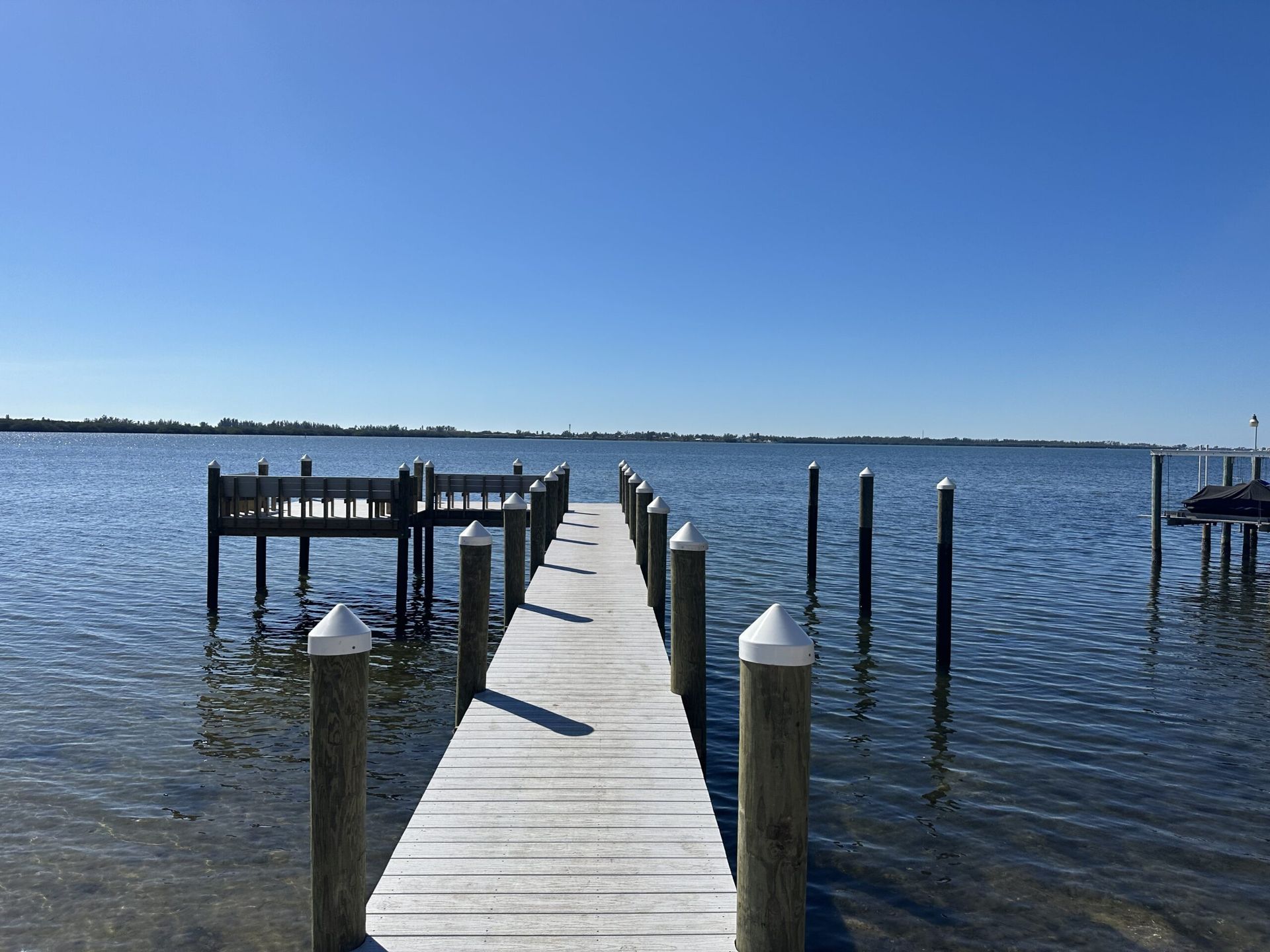 Wooden dock extends into calm water under a clear blue sky.