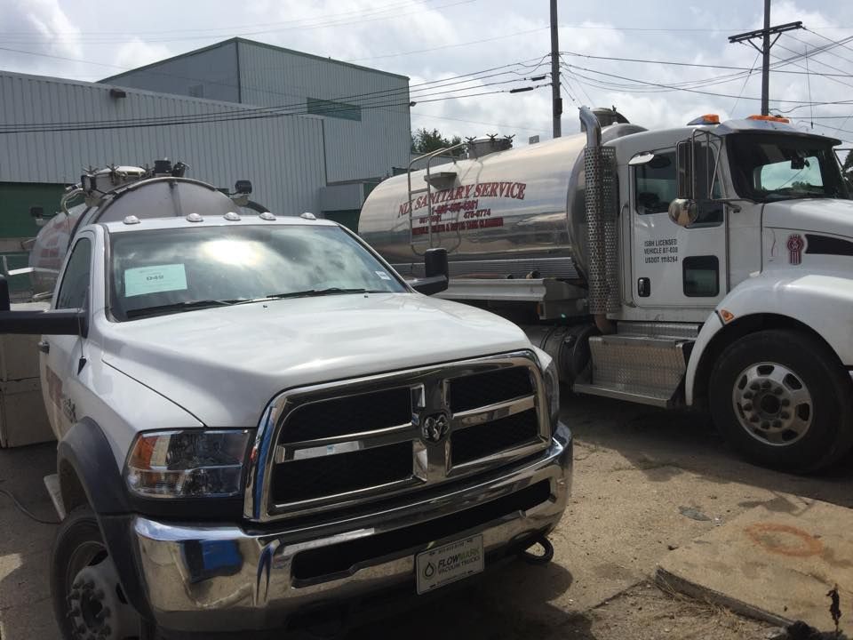 Two white tanker trucks parked outdoors on a sunny day.