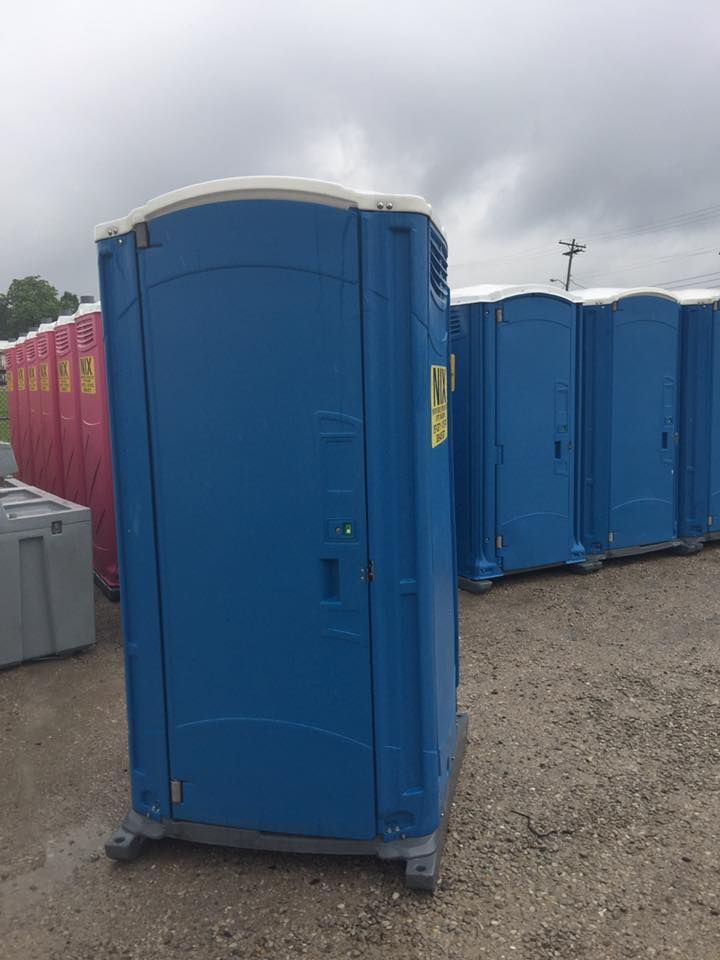 Blue portable toilet, several others in a row, cloudy day.