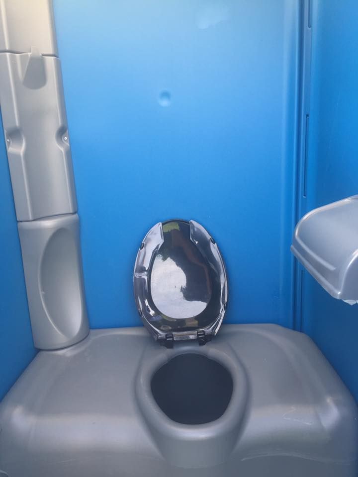 Inside of a blue portable toilet; grey toilet seat and basin, open lid.