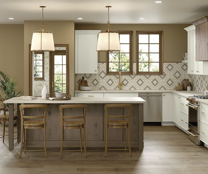 Kitchen with island, white cabinets, patterned backsplash, wood floors, and hanging pendant lights.
