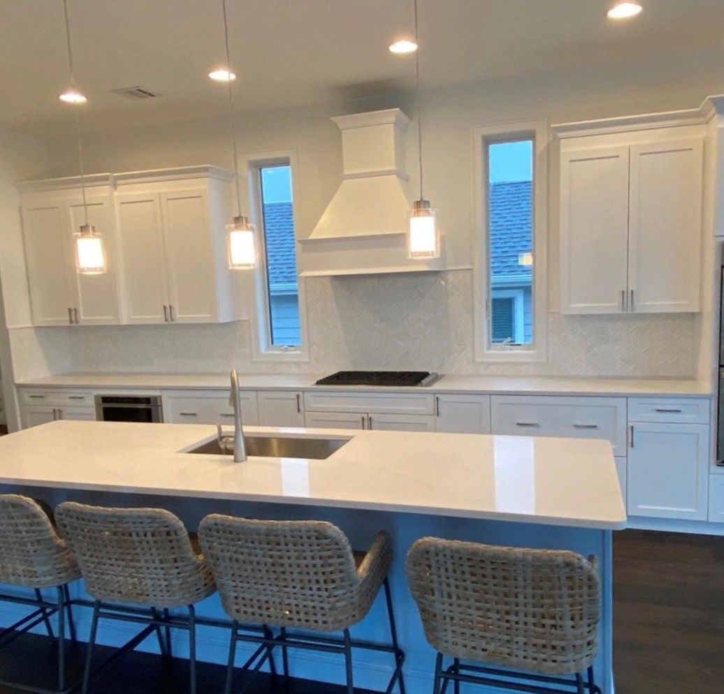 Modern kitchen with white cabinets, island seating, and stainless steel appliances.