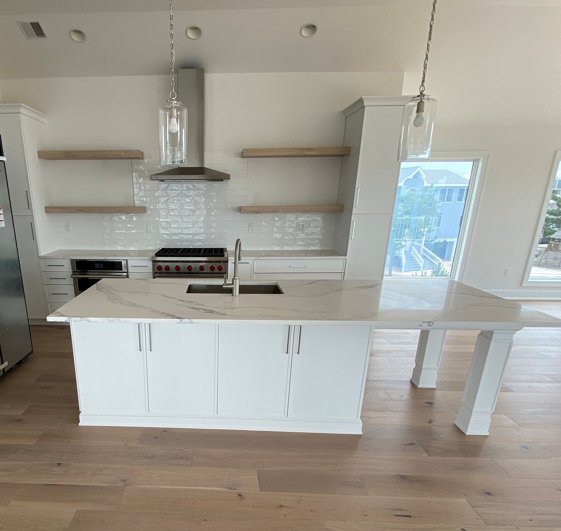 Modern kitchen with white cabinets, island, and stainless steel appliances.
