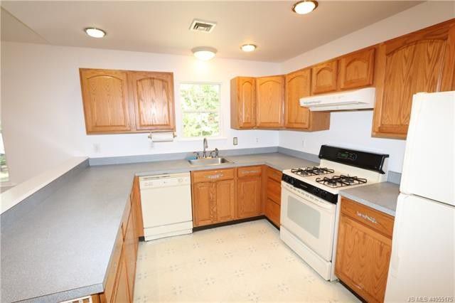 Kitchen with light wooden cabinets, white appliances, and gray countertops.