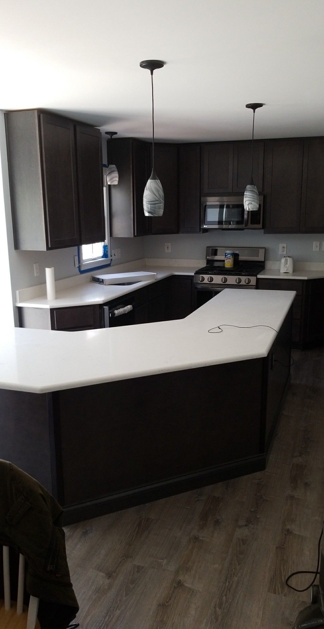 Dark brown kitchen cabinets with a white countertop and two pendant lights.