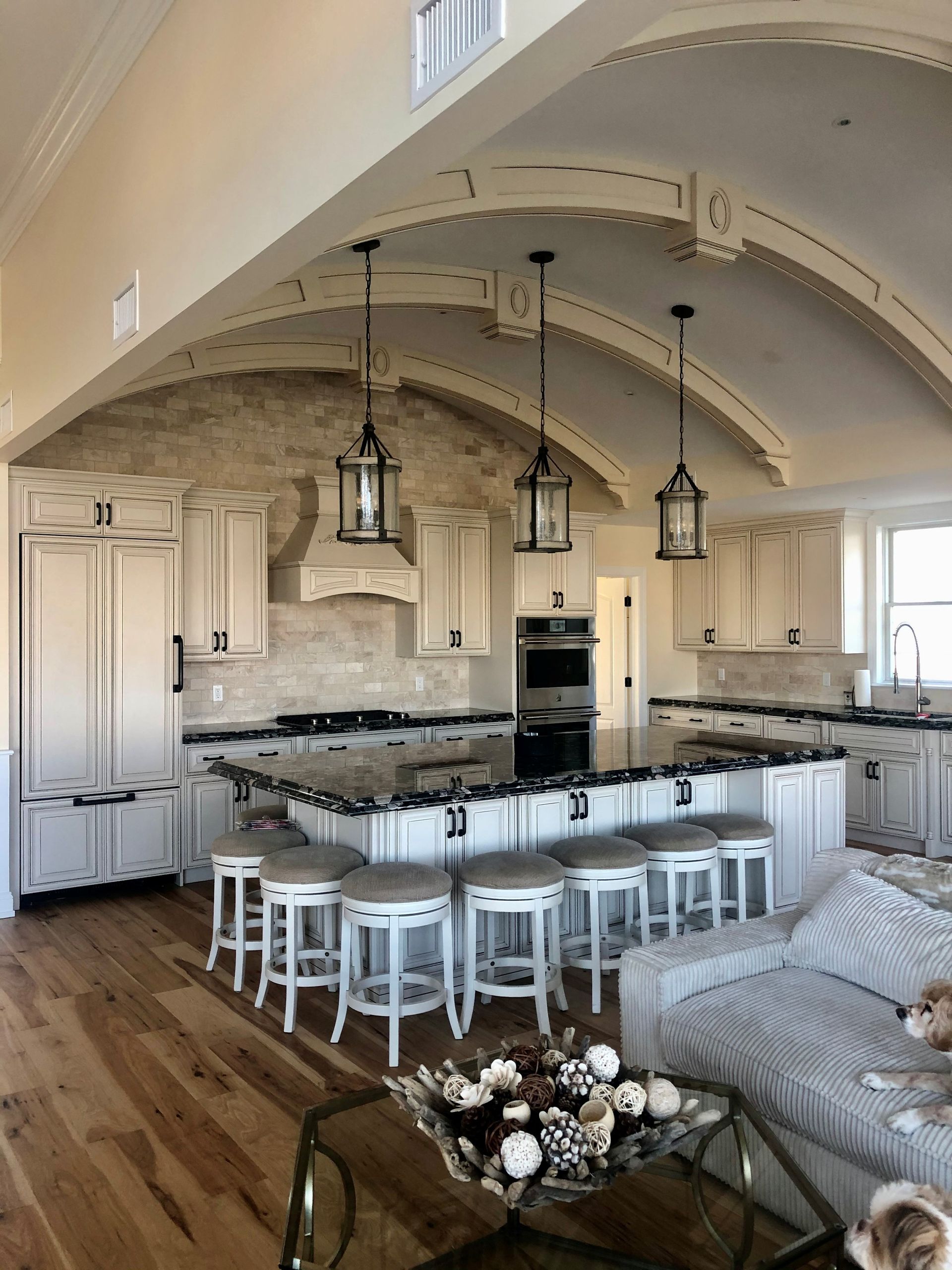 Elegant kitchen with white cabinetry, dark countertops, and a large island with seating.