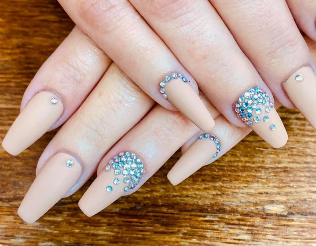 A close up of a woman 's nails with rhinestones on them