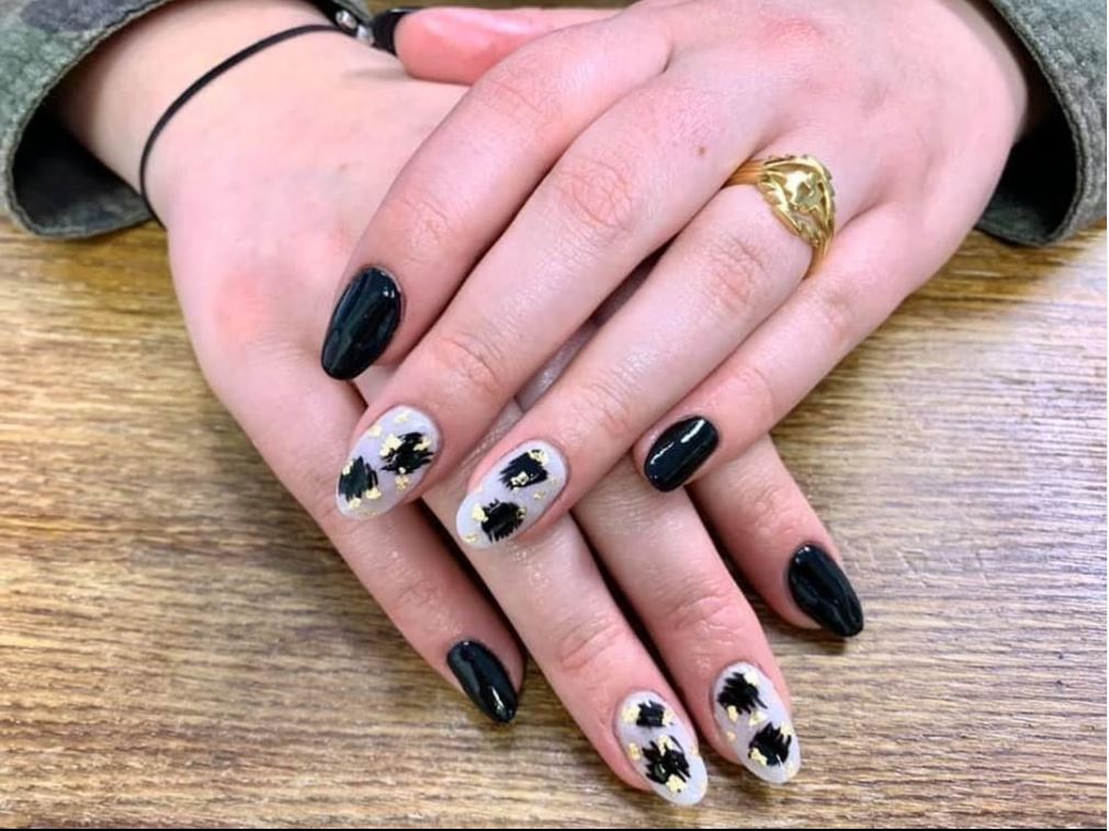 A woman 's hands with black and white nails and a gold ring