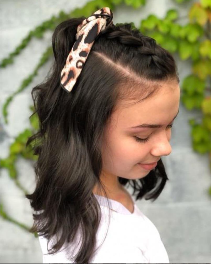 A young girl with a braided ponytail and a leopard print headband