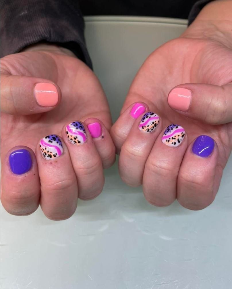 A close up of a person 's hands with purple and pink nails