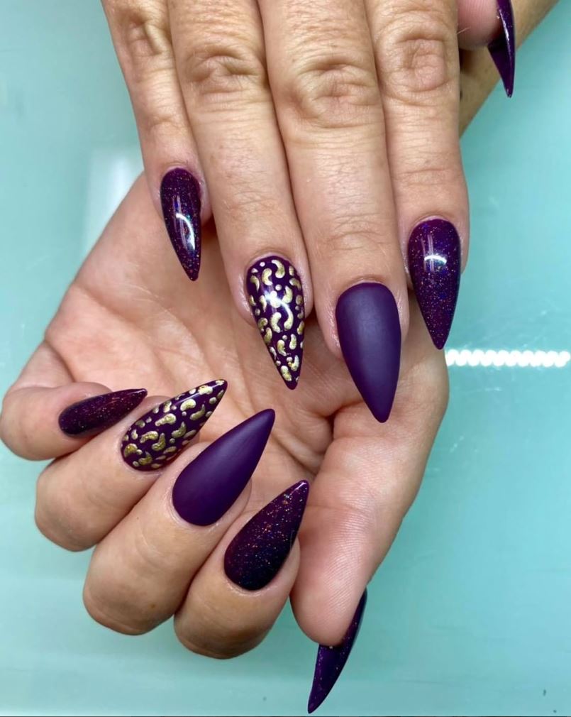 A woman 's hand with purple nails and a leopard print