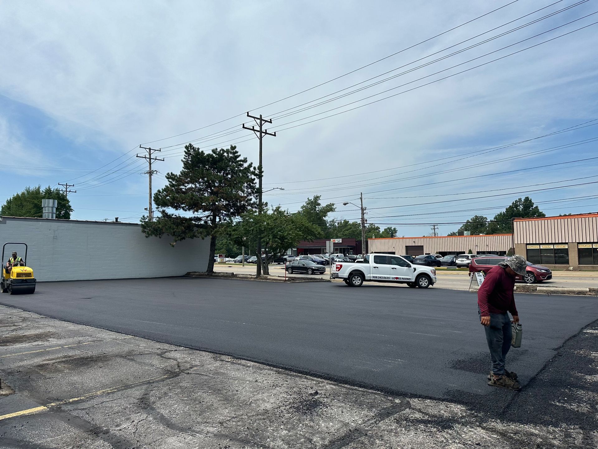 A man is paving a parking lot in front of a building.