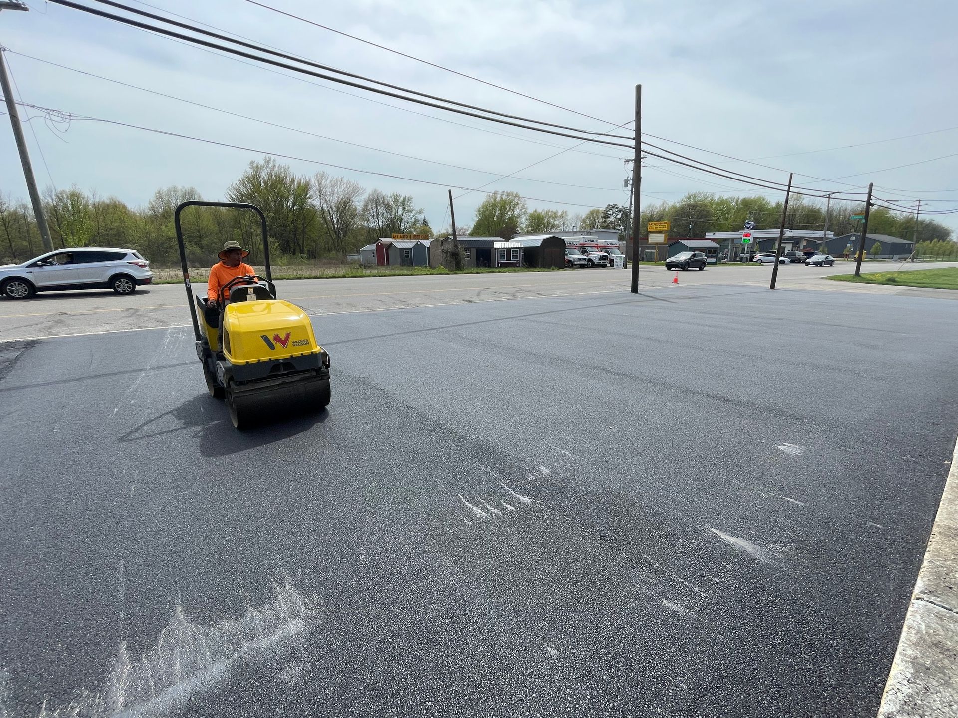 A man is driving a yellow roller on a road.
