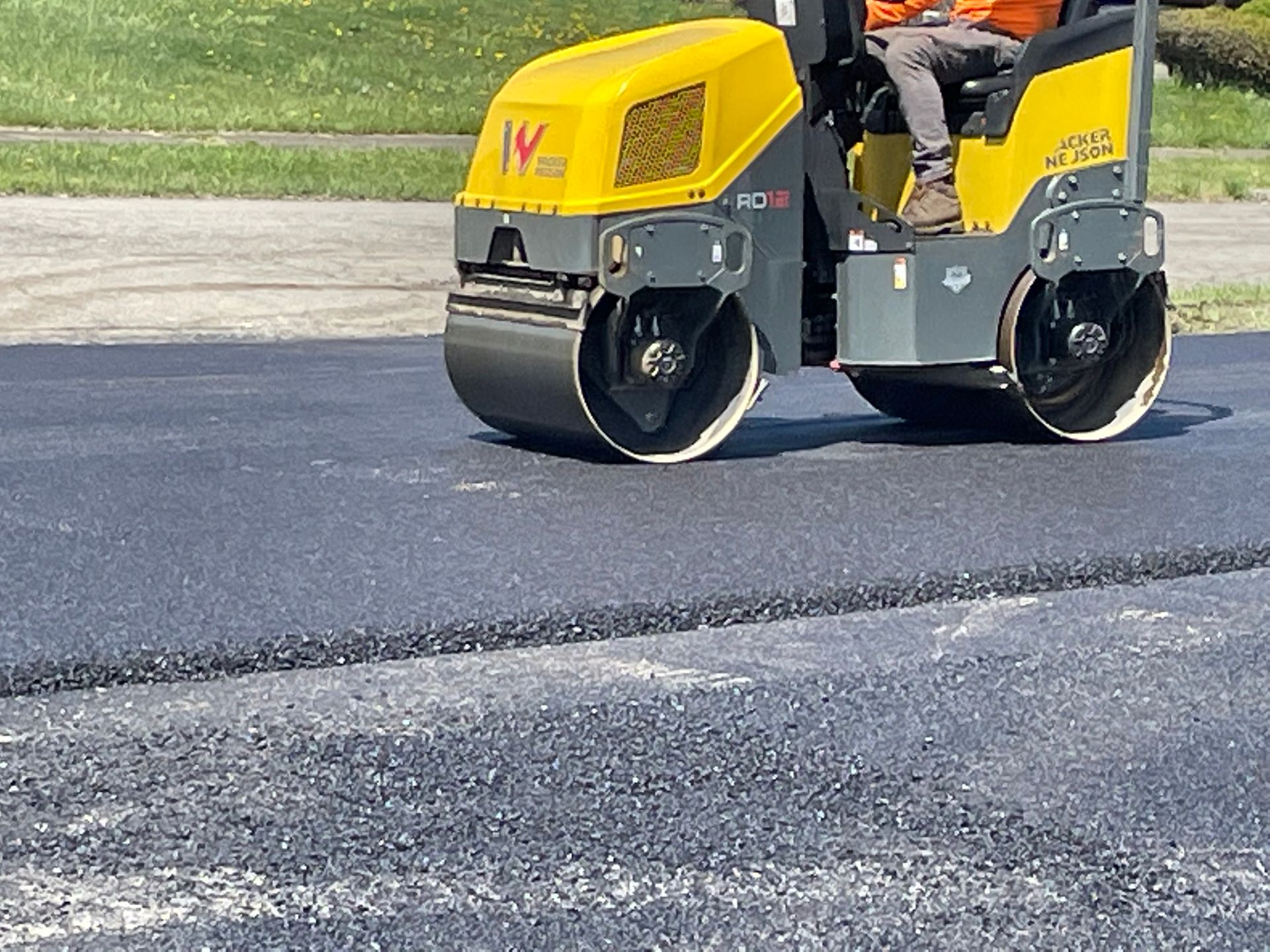 A man is driving a yellow roller on a road