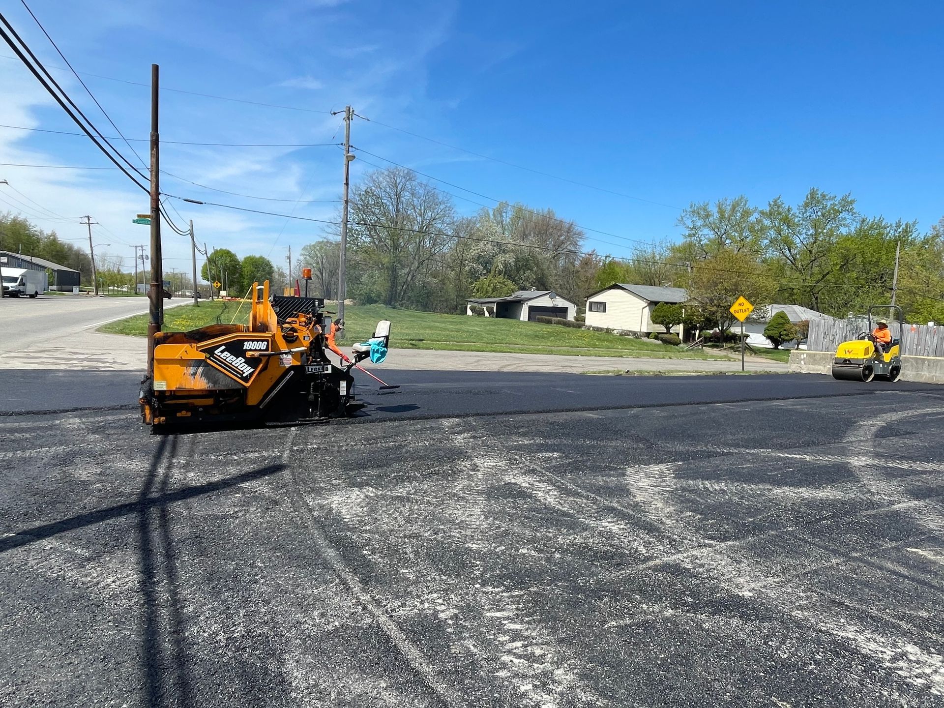 A yellow truck is driving down a road with a yellow sign in the background.
