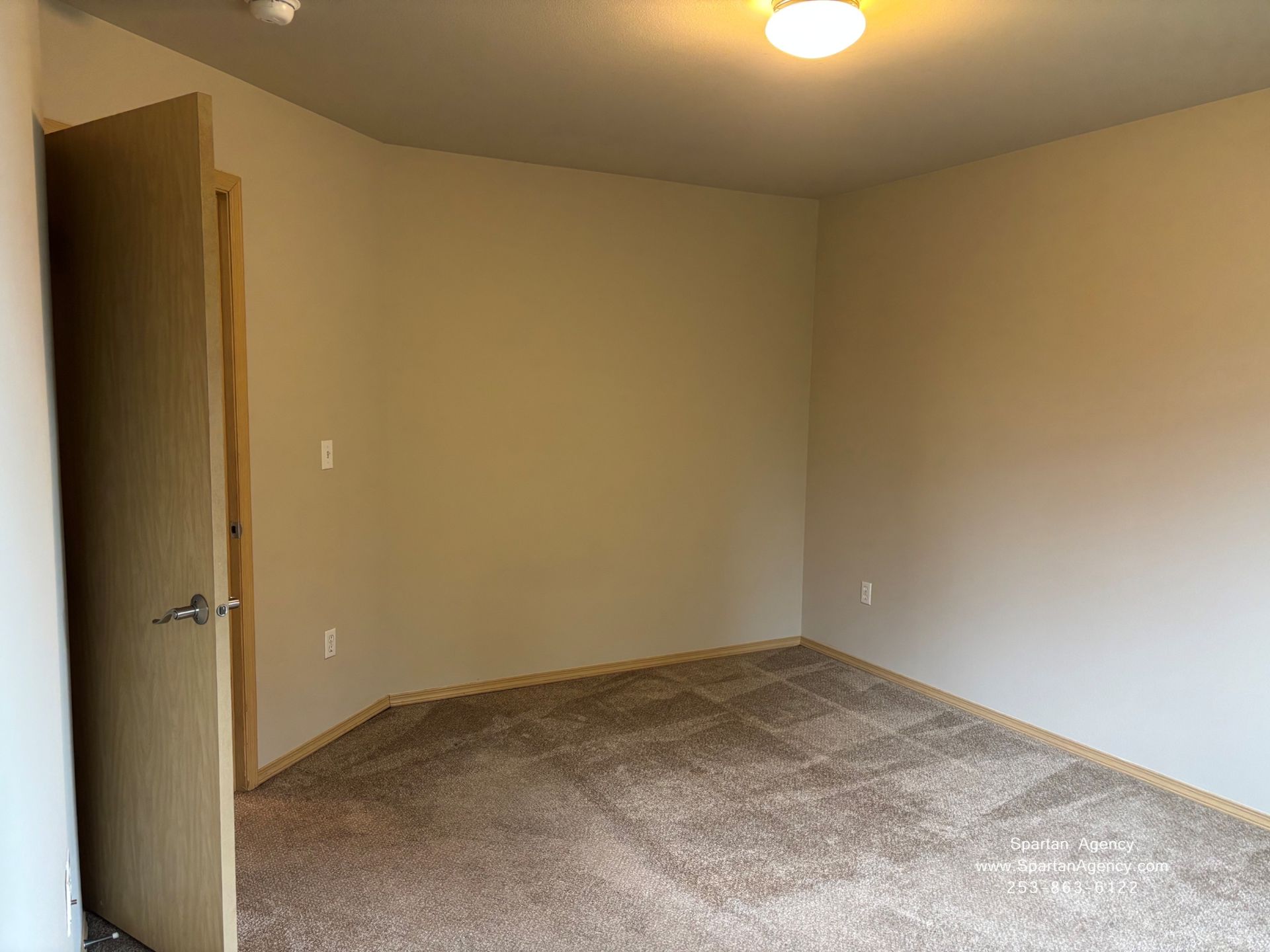 Empty beige bedroom with open door and carpeted floor