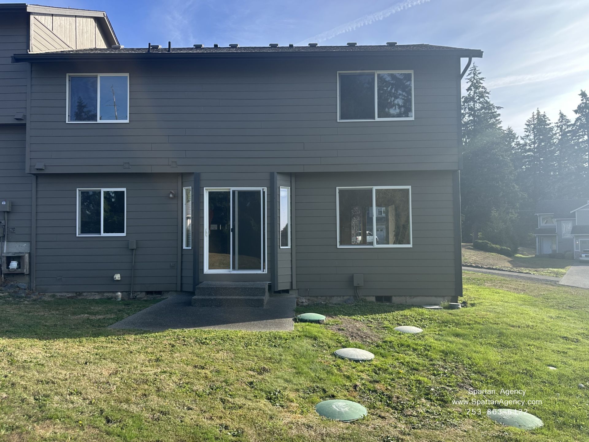 Back of a gray two-story house with a grassy yard and stepping stones