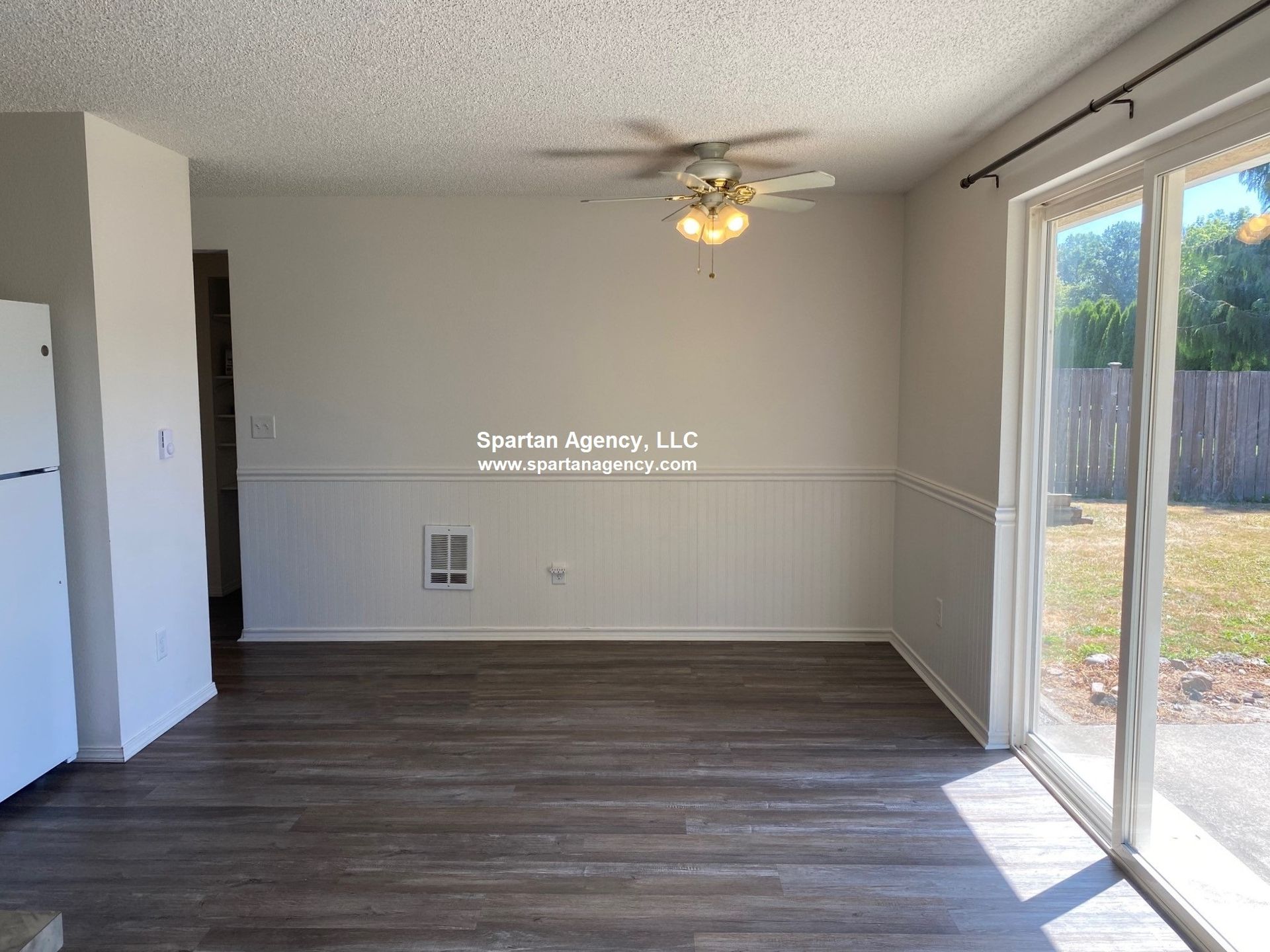 Empty dining room with wood floors, white walls, and sliding glass door.
