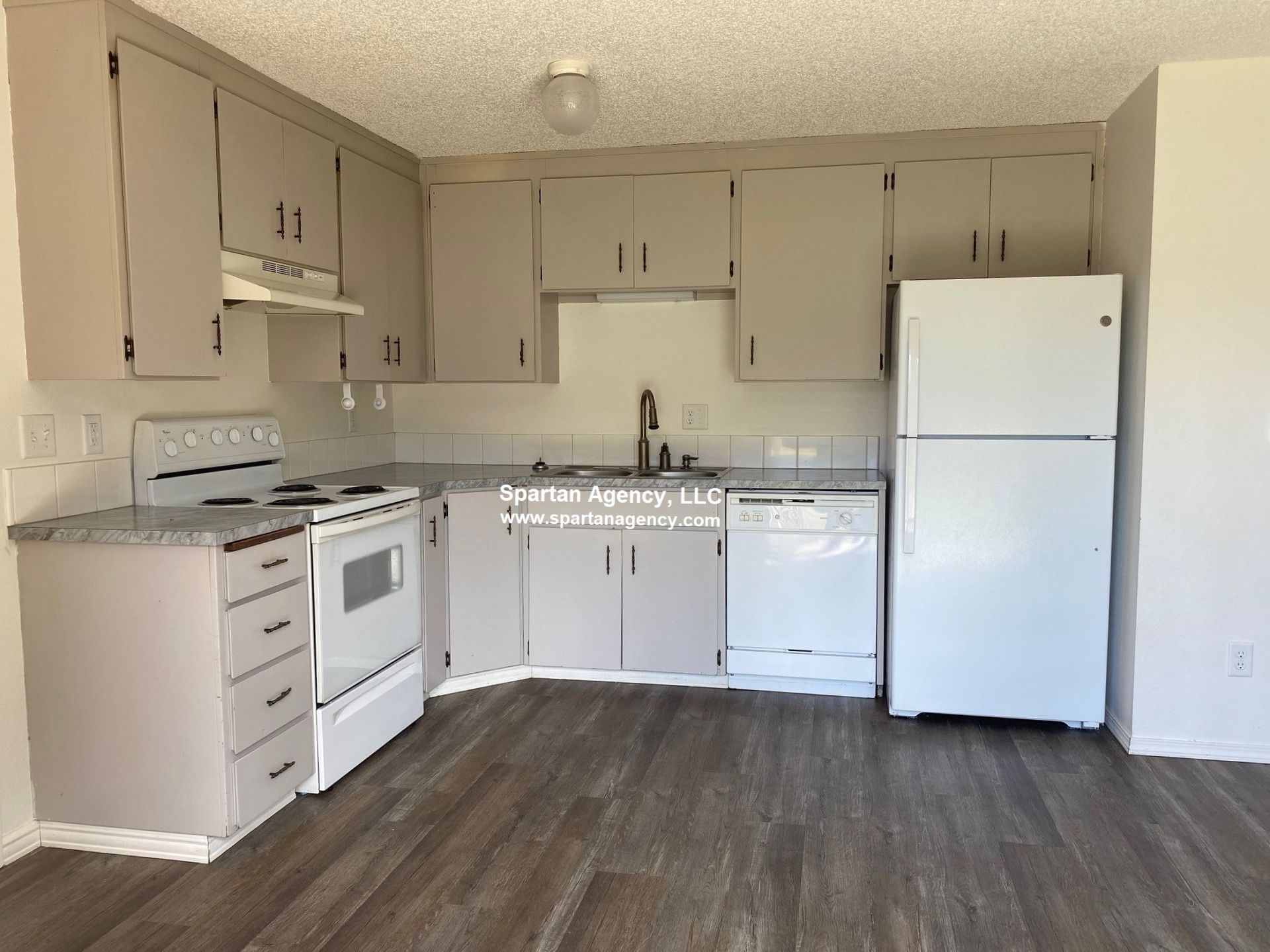 Kitchen with gray cabinets, white appliances, and wood-look flooring.