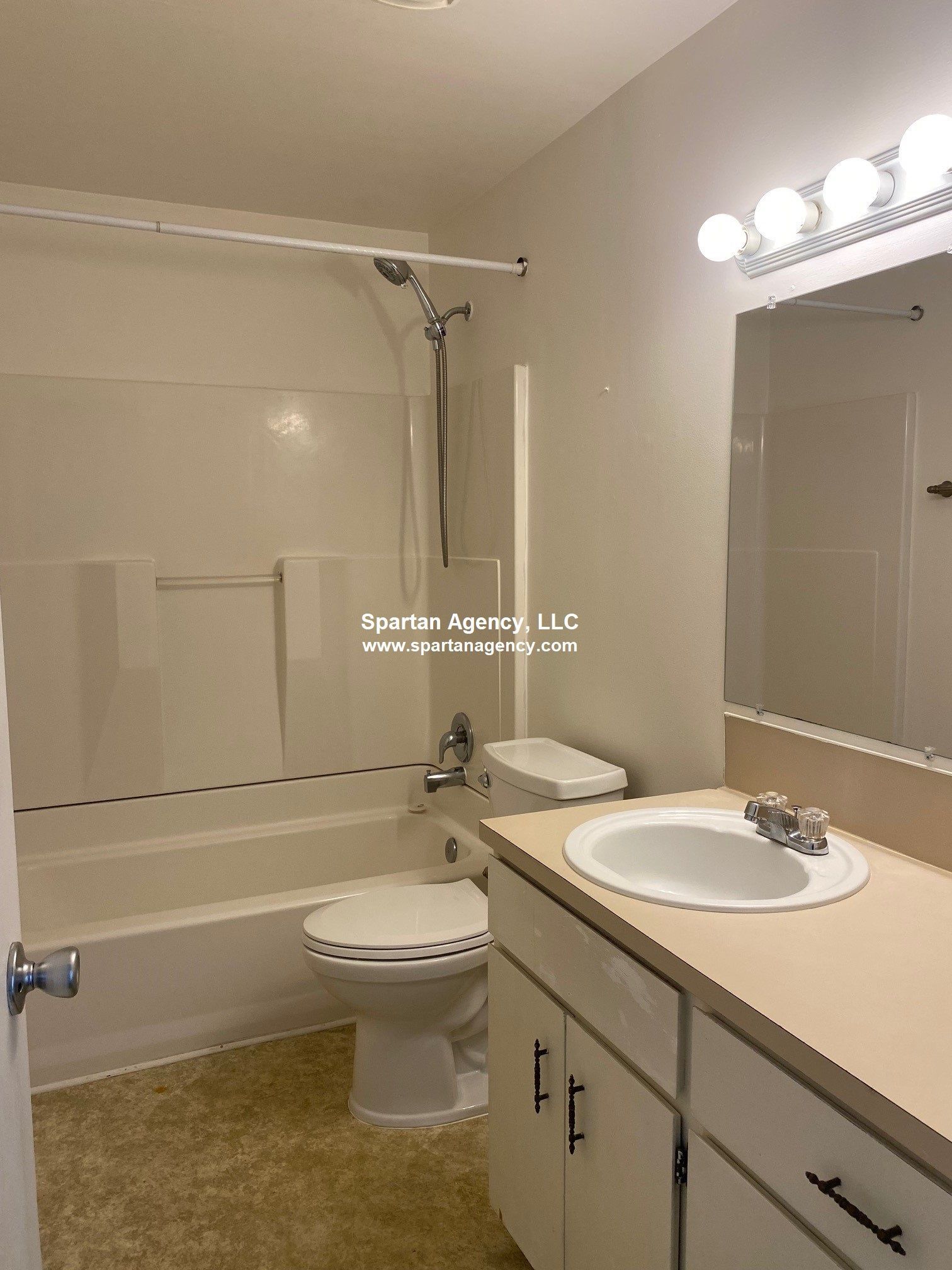 Bathroom with a tub, toilet, sink, and vanity. White and light beige colors throughout.