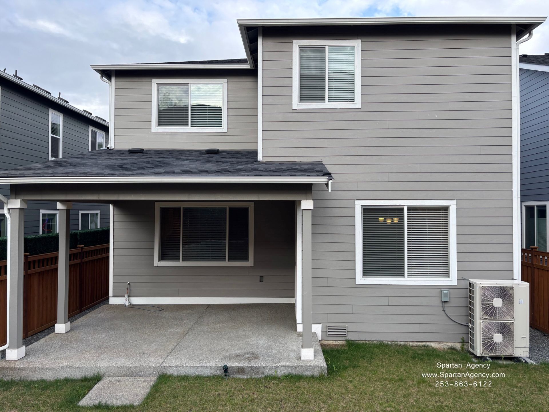 Back of a gray two-story house with a covered patio, windows, and an AC unit on the side.