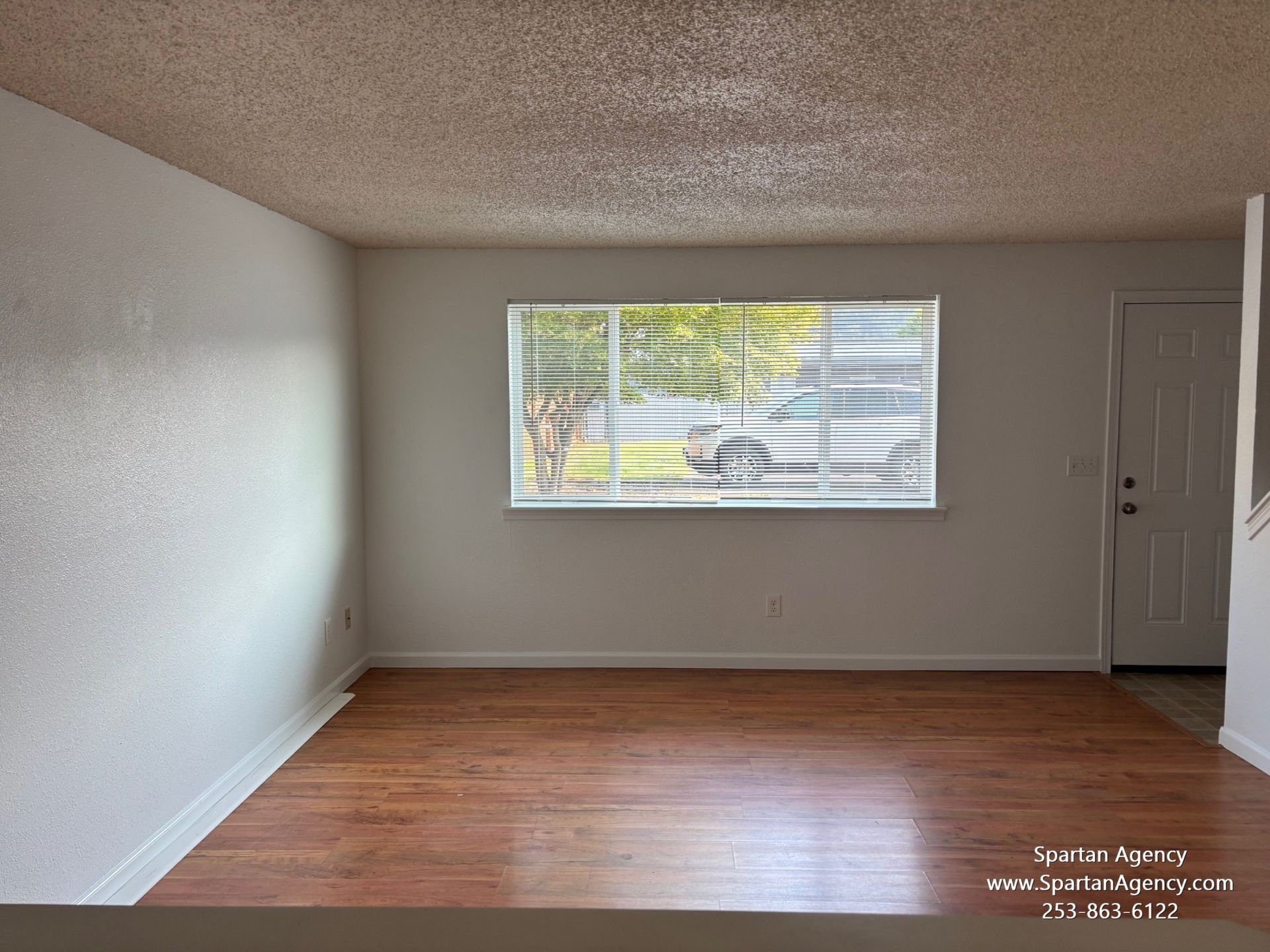 An empty living room with hardwood floors and a window