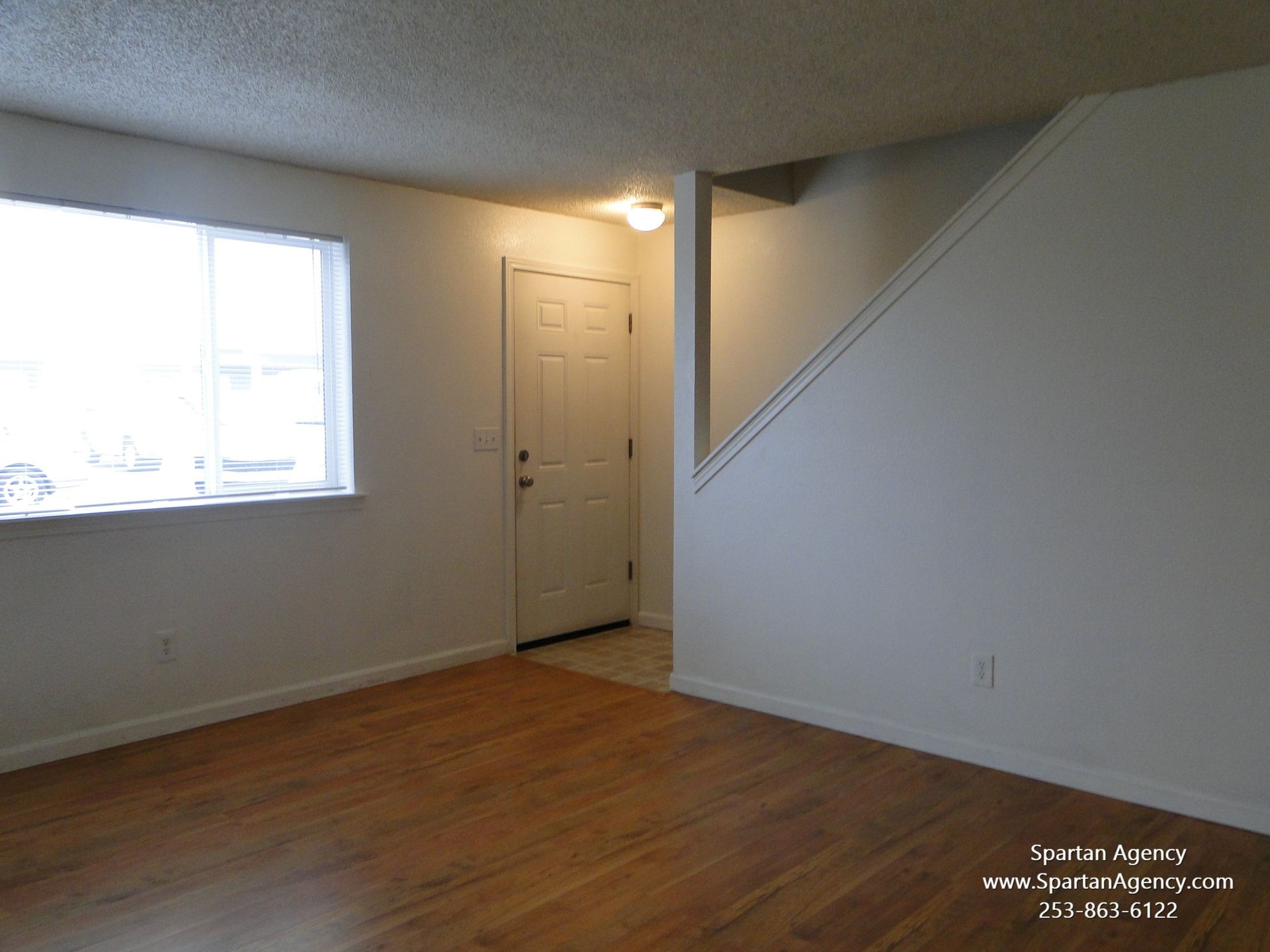 An empty living room with stairs and a window