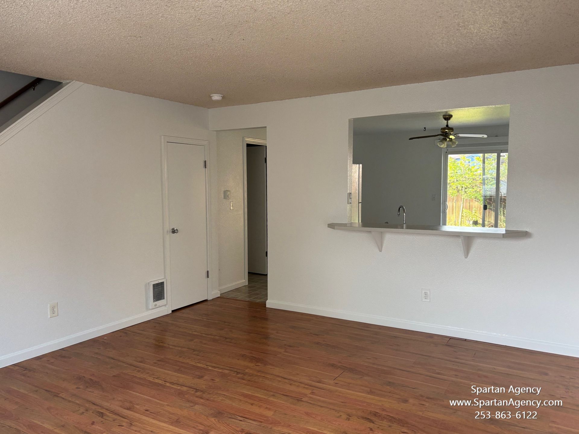 An empty living room with hardwood floors and white walls.
