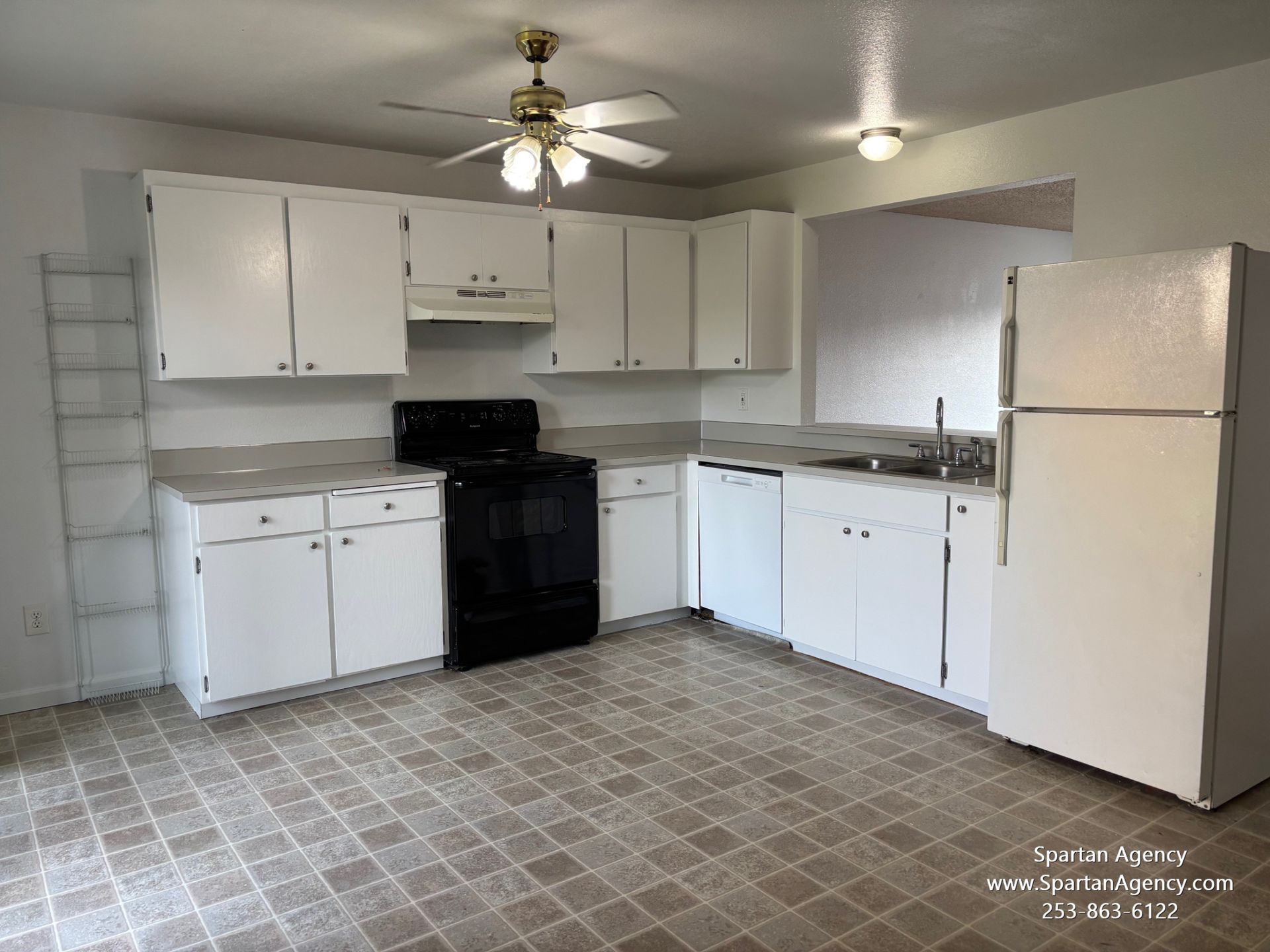 An empty kitchen with white cabinets and a ceiling fan