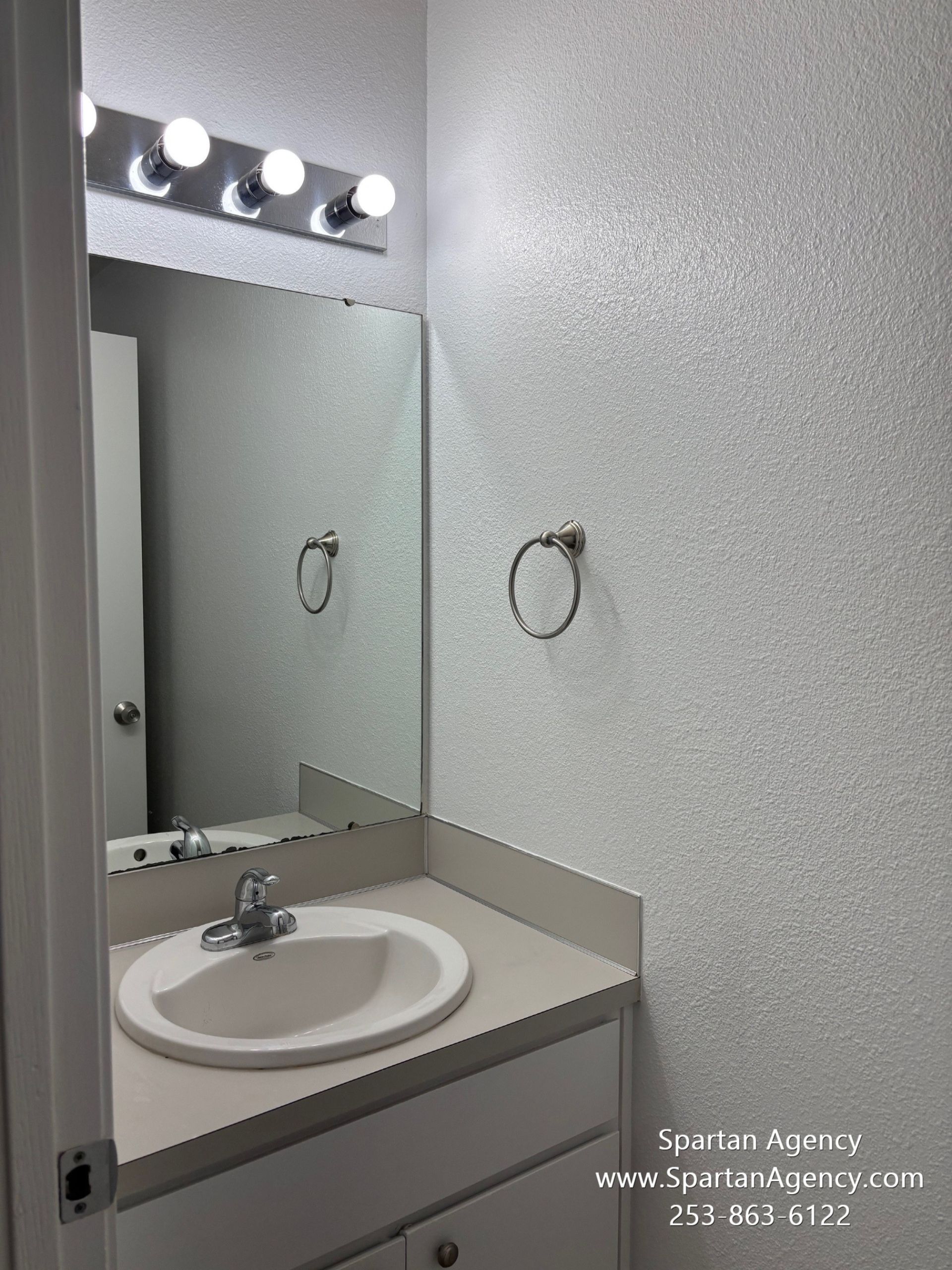 A bathroom with a sink, mirror, and lights.