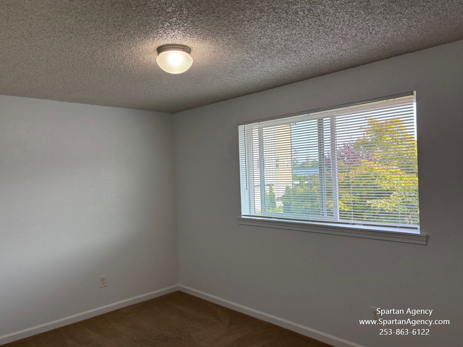 An empty room with a window and blinds on it.