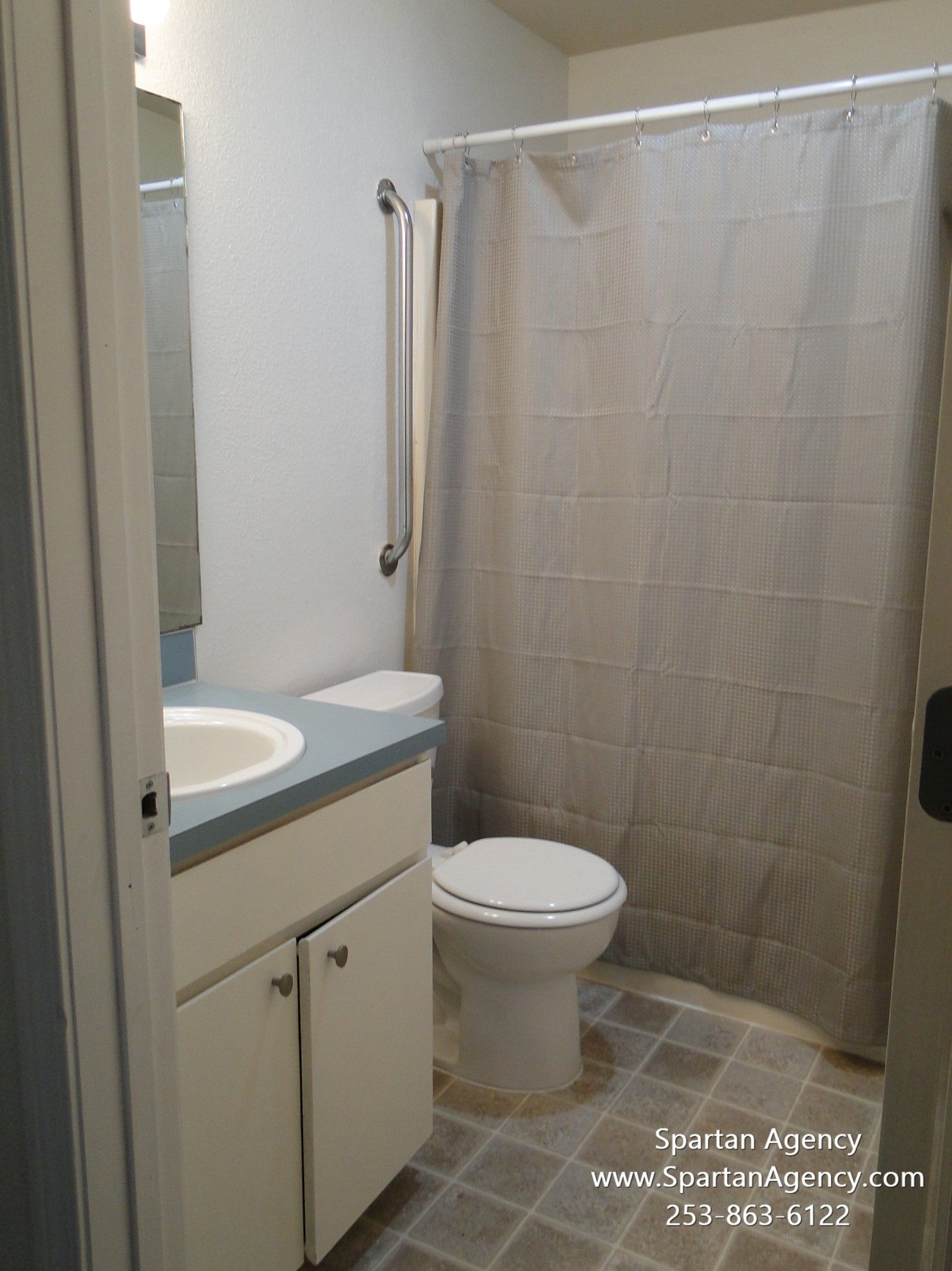 A bathroom with a toilet, sink, mirror, and shower curtain.