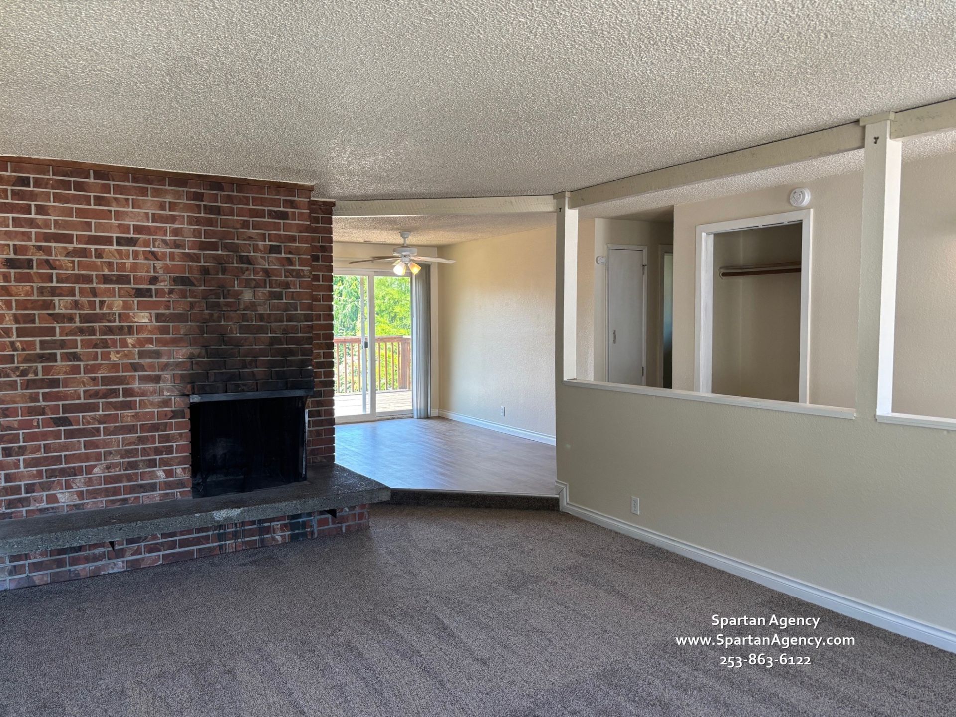 An empty living room with a fireplace and a brick wall
