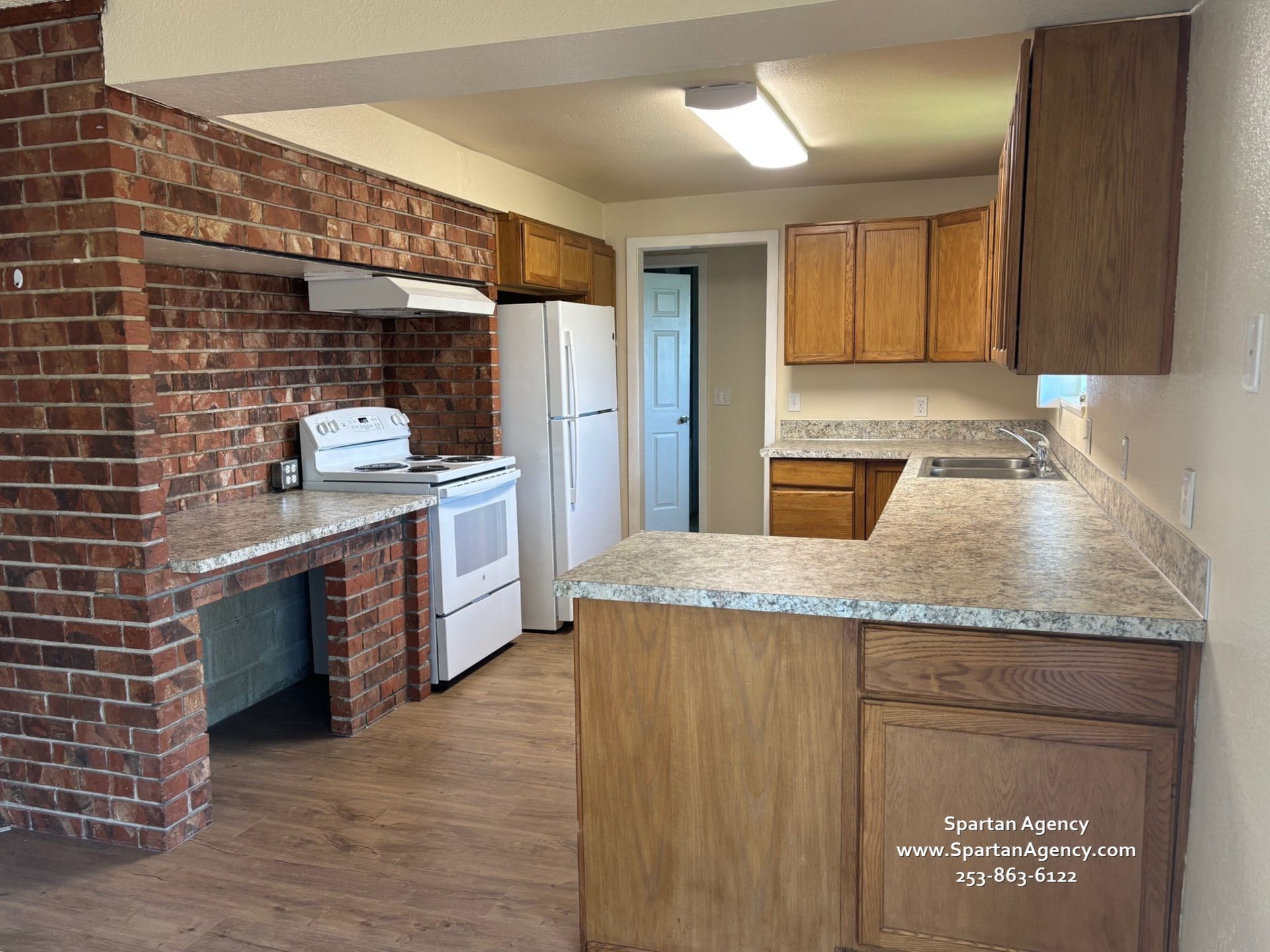 A kitchen with a brick wall and a refrigerator
