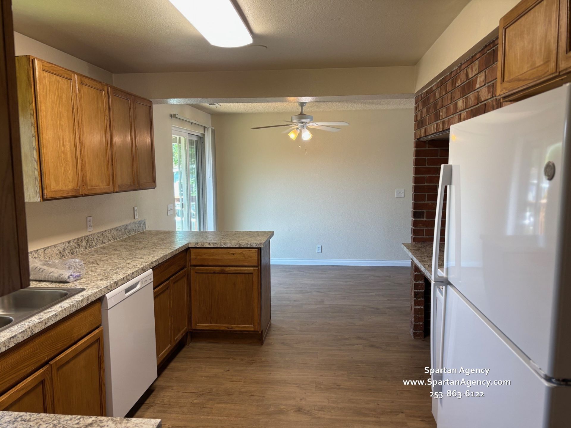 An empty kitchen with wooden cabinets and a white refrigerator