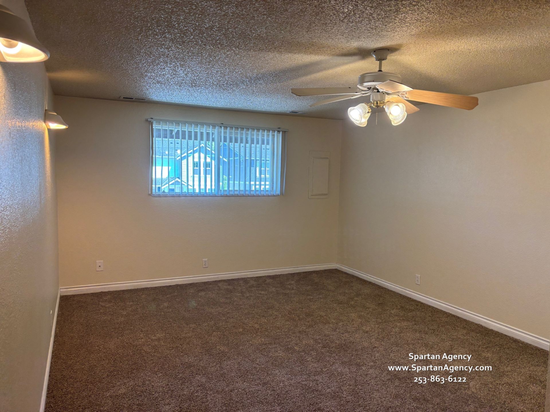 An empty living room with a ceiling fan and a window