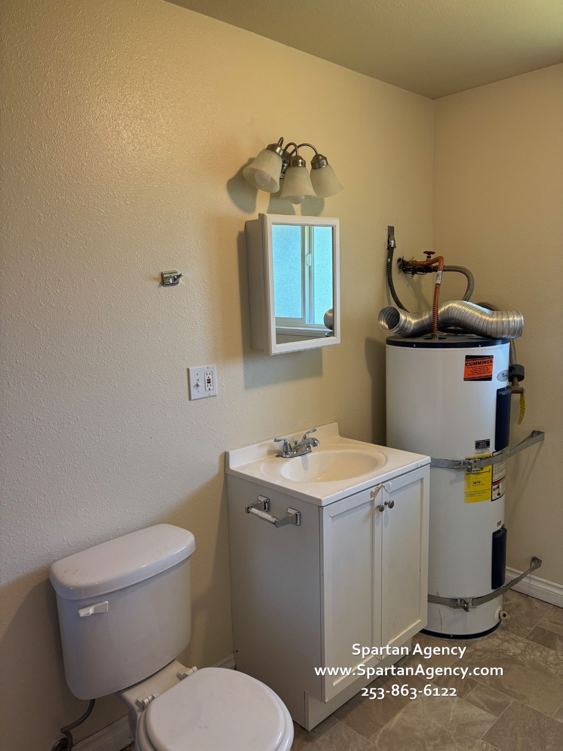 A bathroom with a toilet a sink and a water heater